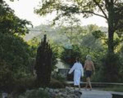 Deux personnes marchent près de la tente Glamping «Arriba» au Resort de Parel, Pays-Bas, entourés de verdure.