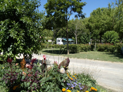 Kleurrijke bloemenperk en veel groen op Onlycamp Camping de l'Argenté in Occitanië, Frankrijk, met caravan.