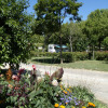 Colorful flowers and lush greenery at Onlycamp Camping de l'Argenté holiday park in Occitanie, France, with a caravan.