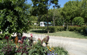 Colorful flowers and lush greenery at Onlycamp Camping de l'Argenté holiday park in Occitanie, France, with a caravan.