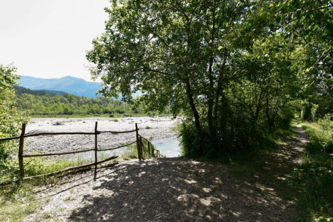 Sti ved flod og træer i Onlycamp Camping Les Tuillères, et feriepark i Auvergne-Rhône-Alpes, Frankrig.