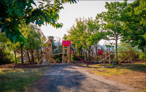 Legeplads med rutsjebane og træstruktur omgivet af træer i Onlycamp Camping Les Vailhès, Occitanie.