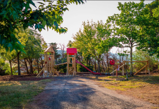 Parque infantil con tobogán y estructuras de madera en Onlycamp Camping Les Vailhès, Occitania, Francia.