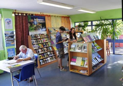 Innenraum des Onlycamp Camping de Besançon, wo Menschen Zeitschriften und Bücher anschauen.