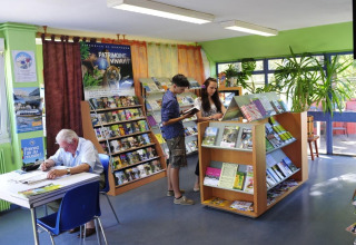 Binnen bij Onlycamp Camping de Besançon, mensen lezen brochures en ontspannen in de leeshoek.