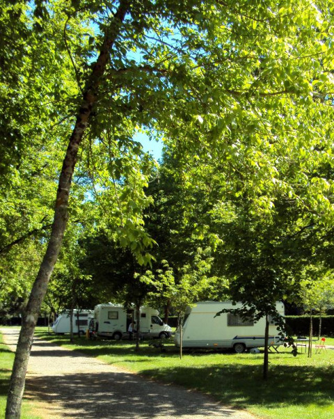 Kampeerplek met caravans onder groene bomen bij Onlycamp Camping de l'Argenté in Occitanië, Frankrijk.