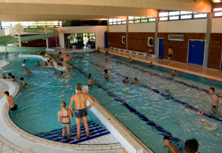Indoor swimming pool at Onlycamp Camping le Champ d'Été, Auvergne-Rhône-Alpes, France, with many swimmers.
