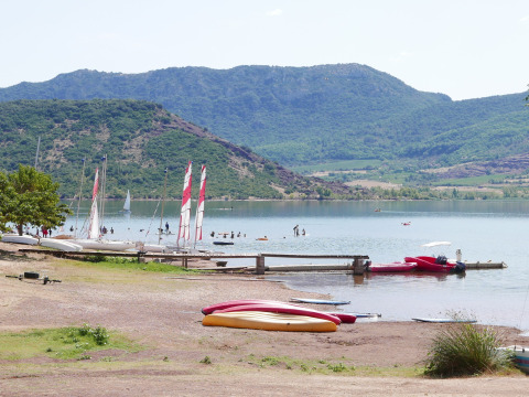 Udsigt over søen ved Onlycamp Camping Les Vailhès, med både og bjerge i baggrunden, Occitanie, Frankrig.