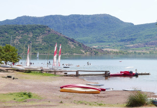 Uitzicht op het meer bij Onlycamp Camping Les Vailhès met boten en bergen in Occitanië, Frankrijk.