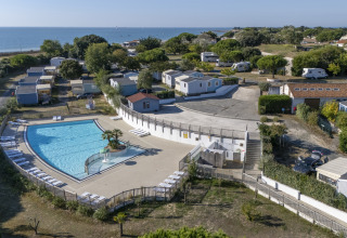 Luftaufnahme vom Flower Camping Le Platin - La Redoute Ferienpark mit Pool, Mobilheimen und Meerblick.