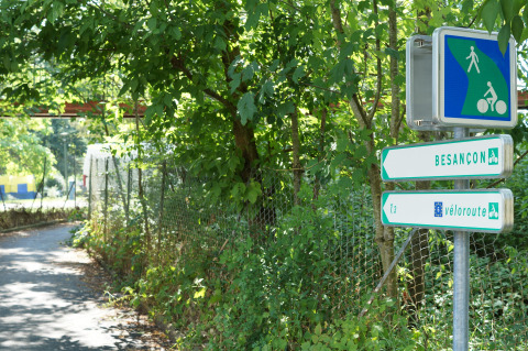 Pathway at Onlycamp Camping de Besançon with signs to Besançon and véloroute in Bourgogne-Franche-Comté, France.