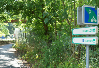 Pathway at Onlycamp Camping de Besançon with signs to Besançon and véloroute in Bourgogne-Franche-Comté, France.