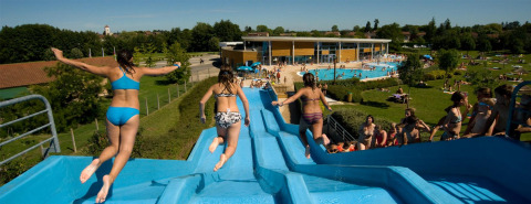 Children enjoy sliding down a water slide at Onlycamp Camping le Champ d'Été holiday park in France.