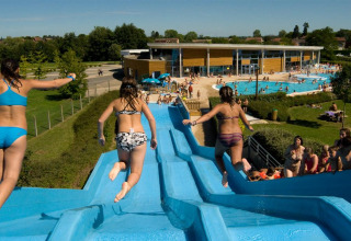 Children enjoy sliding down a water slide at Onlycamp Camping le Champ d'Été holiday park in France.