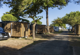 Wooden cabins and campervans among trees at Flower Camping Le Platin - La Redoute, Île de France.