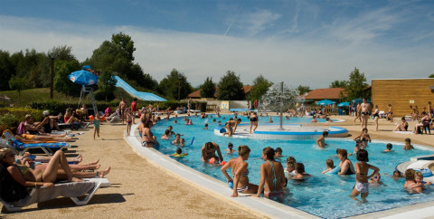 Gezinnen genieten van zwemmen en zonnen bij het zwembad van Onlycamp Camping le Champ d’Eté in Frankrijk.