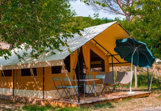 Safari Ponza telt med terrasse, stole, bord og parasol omgivet af træer i naturskønne omgivelser.