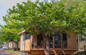 Tienda de safari Tiny House Galli bajo árboles verdes en Onlycamp Camping Les Vailhès, Francia.