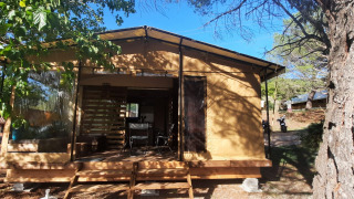Glamping-Unterkunft mit Holzterrasse und Zelttuchwänden in einem bewaldeten Campingplatz.
