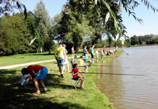 Vakantiepark in Auvergne-Rhône-Alpes, Frankrijk, waar gezinnen en kinderen vissen aan het meer.
