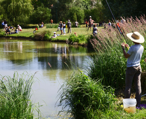 People are fishing by a pond at Onlycamp Camping le Champ d'Été holiday park, Auvergne-Rhône-Alpes, France.