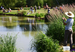 People are fishing by a pond at Onlycamp Camping le Champ d'Été holiday park, Auvergne-Rhône-Alpes, France.