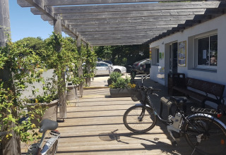 Udendørs terrasse med cykler, grønne planter i krukker og træpergola ved Flower Camping Le Platin, Île de France.