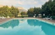 Udendørs swimmingpool med liggestole, omgivet af træer og bjerge ved Onlycamp Camping Chamarges i Frankrig.