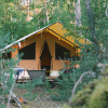Large modern tent set among trees at Camping Onlycamp Les Pins, Centre-Val de Loire, France, in a forest.