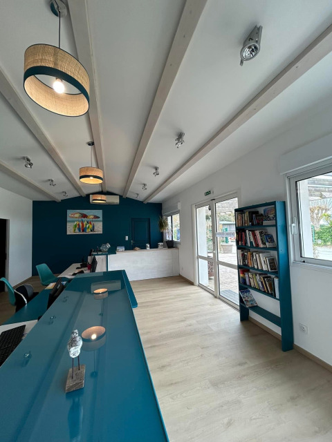 Empfangsbereich von Flower Camping Le Platin - La Redoute mit blauer Wand, Bücherregal und Schreibtischen.