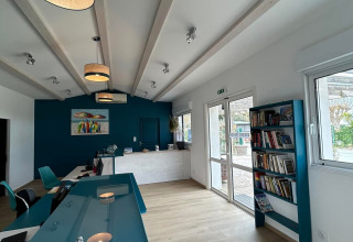 Receptie van Flower Camping Le Platin - La Redoute met blauwe muur, boekenrek en uitnodigende sfeer.