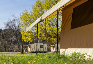 Buitenzicht op tenten en kleine hutten tussen het groen bij Onlycamp Camping Chamarges, Frankrijk.