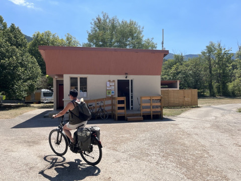 Cyclist rides past a small building at Onlycamp Camping Chamarges holiday park in Auvergne-Rhône-Alpes, France.