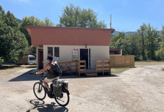 Fietser passeert een klein gebouw aan Onlycamp Camping Chamarges in Auvergne-Rhône-Alpes, Frankrijk.