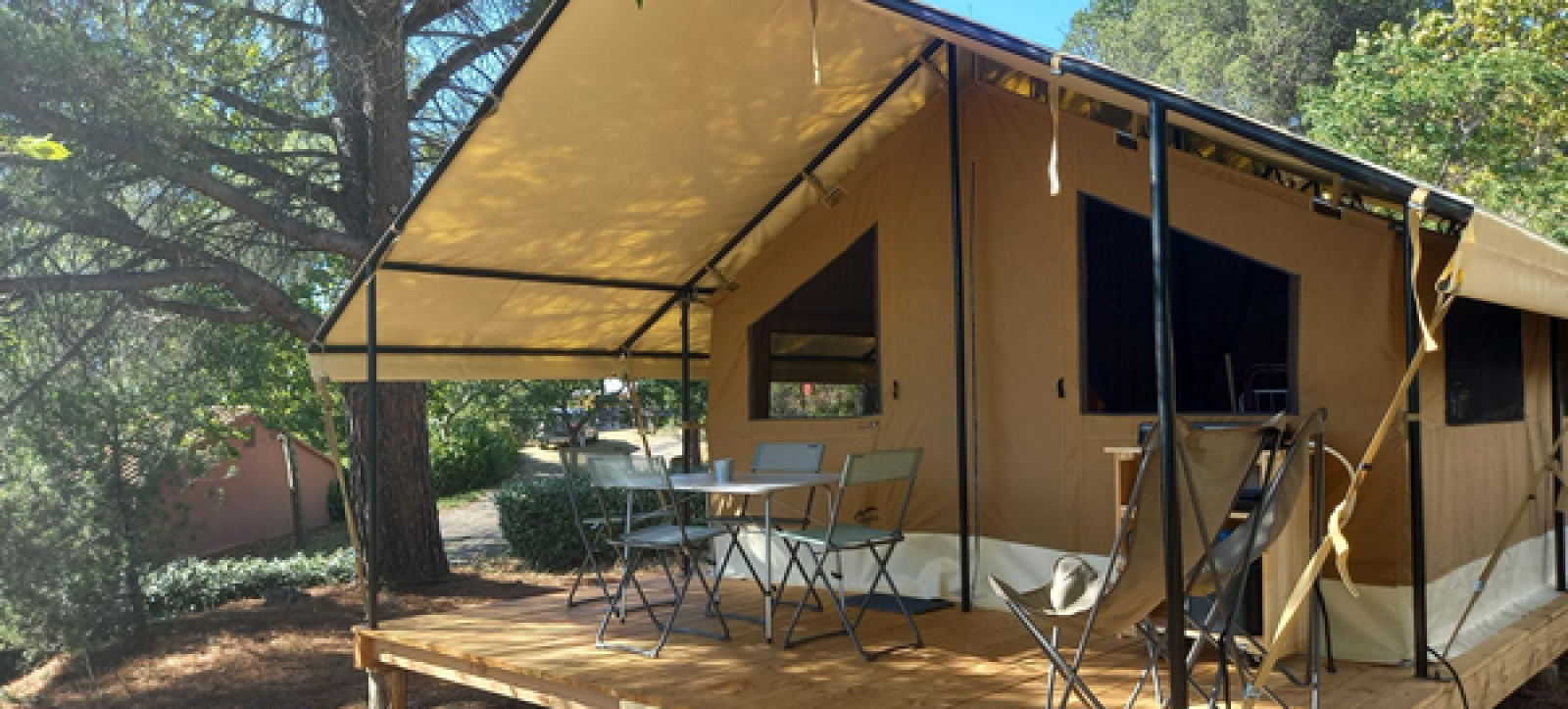 Ponza safaritent met overdekt terras, tuinstoelen en natuur op een rustige campinglocatie.