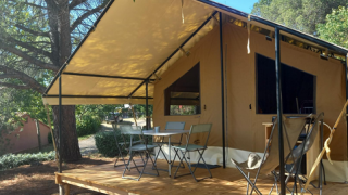 Tente safari Ponza avec terrasse couverte, mobilier de jardin et cadre naturel sur un terrain de camping.