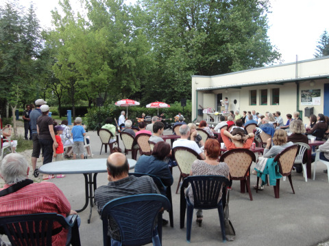 Menschen sitzen draußen bei einer Veranstaltung im Onlycamp Camping de Besançon in Bourgogne-Franche-Comté, Frankreich.