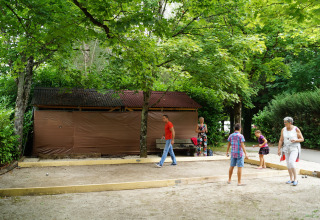 Personas juegan a la petanca en un área sombreada de Onlycamp Camping de Besançon en Borgoña-Franco Condado, Francia.