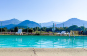 Buitenzwembad met ligbedden en uitzicht op bergen bij Onlycamp Camping Chamarges, Frankrijk.
