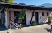 Buitenaanzicht van Onlycamp Camping Les Thézières met fiets, planten en bergen op de achtergrond.