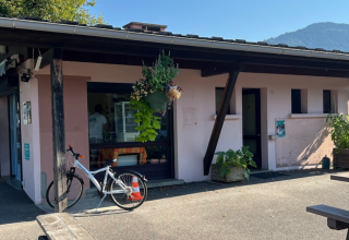 Buitenaanzicht van Onlycamp Camping Les Thézières met fiets, planten en bergen op de achtergrond.