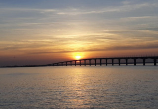 Mooie zonsondergang boven het water met een lange brug bij Rivedoux-Plage, Île de Ré, Frankrijk, op de achtergrond.