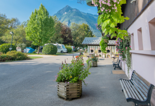 Scenic view of Onlycamp Camping Les Thézières with mountain backdrop, greenery, benches, and flower boxes.
