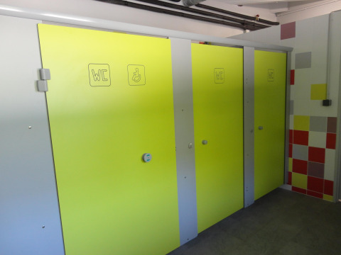 Bright yellow restroom stalls at Onlycamp Camping de Besançon holiday park in Bourgogne-Franche-Comté, France.