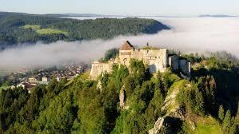 Luftfoto af et slot omgivet af skov og tåge nær Chalezeule i Bourgogne-Franche-Comté, Frankrig.