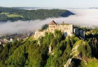 Luftfoto af et slot omgivet af skov og tåge nær Chalezeule i Bourgogne-Franche-Comté, Frankrig.