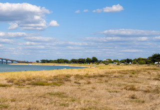 Küstenlandschaft mit Grasfläche, Meer, Brücke und Ferienpark bei Flower Camping Le Platin - La Redoute, Île de France.