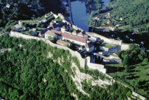 Aerial view of a historic fortress on a forested hill near Chalezeule in Bourgogne-Franche-Comté, France.
