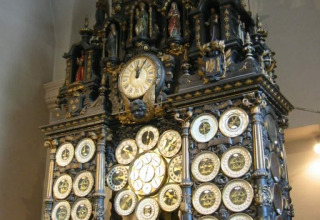 Oude astronomische klok met meerdere wijzerplaten en sierlijke beelden tentoongesteld in een historisch gebouw.