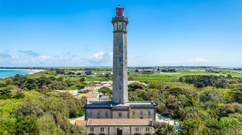 Et højt fyrtårn omgivet af grønne marker og skov nær kysten i nærheden af Rivedoux-Plage, Île de Ré, Frankrig.